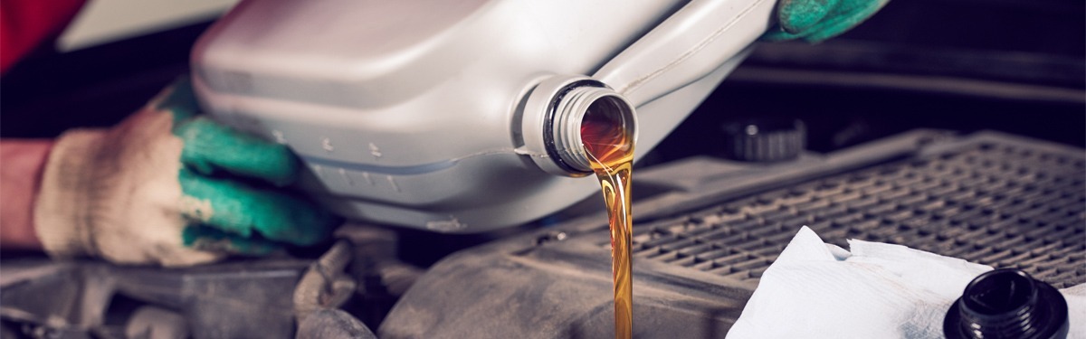Mechanic pouring engine oil into the engine as part of a car service.