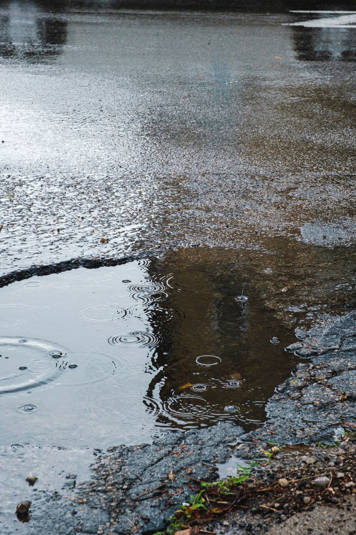 A medium pothole full of rain water on a busy UK road.