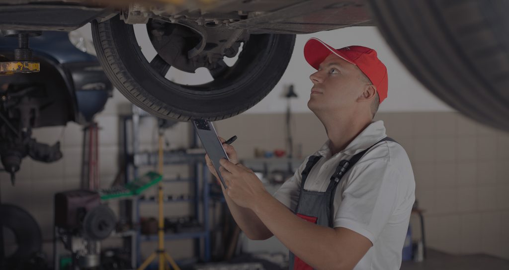 Man with clipboard checks underneath car
